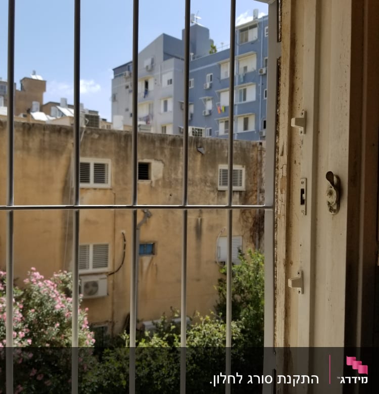 חלון עם סורגים מול בניינים בעיר